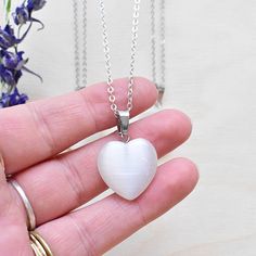 This necklace is made from a white cats eye stone which has been cut into an heart. The stone hangs from a silver plated chain. You can choose the length of the necklace you prefer. You will get a necklace at random. Please note that all necklaces are handmade and may differ from the pictured. The picture shows multiple necklaces. You will receive one necklace with one pendant. Ewelina Pas Jewelry White Heart Pendant Necklace With Spiritual Style, White Heart Pendant Necklace In Spiritual Style, Silver Moonstone Heart Pendant Jewelry, White Spiritual Jewelry With Heart Charm, White Heart-shaped Crystal Necklace For Gift, White Heart-shaped Crystal Necklace Gift, White Sterling Silver Crystal Necklace For Gift, White Sterling Silver Crystal Necklace As Gift, White Heart-shaped Moonstone Jewelry