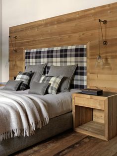 a bed with pillows and blankets on top of it next to a wooden headboard