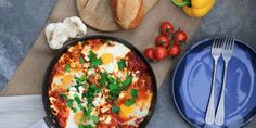 an omelet in a pan with tomatoes, garlic and bread on the side