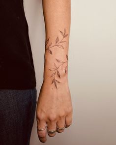 a woman's hand with a small tattoo on her left wrist and the other arm