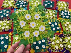 a hand holding a piece of paper that has been made to look like flowers and grass