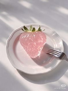 a strawberry sitting on top of a white plate with a knife and fork next to it