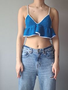 a woman in jeans is wearing a blue crochet top and has her hands on her hips