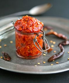 a glass jar filled with red sauce on top of a metal plate