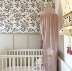 a baby's crib in front of a floral wallpaper