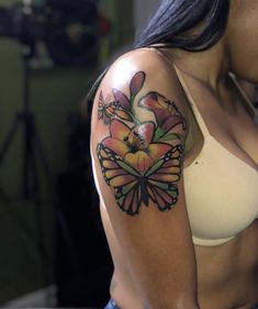 a woman with a butterfly tattoo on her arm and chest, showing off her breast