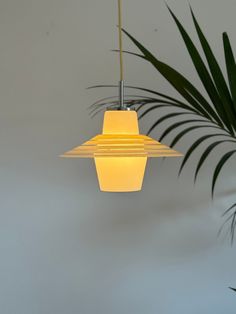 a yellow light hanging from a ceiling next to a plant