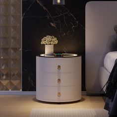 a night stand with flowers on it next to a bed in a room that has black and white walls