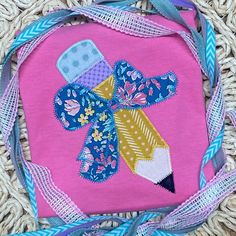 a pink bag with a blue ribbon around it and a cross on the front that is made out of fabric