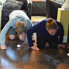 two people are playing on the floor in front of a table with balls and remotes