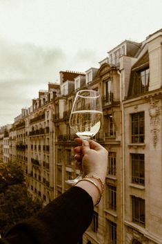 a person holding up a wine glass in front of a cityscape with tall buildings