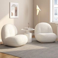 two white chairs sitting on top of a rug in a living room next to a window