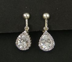 Pair of clear and silver clip on earrings feature a larger CZ teardrop in the center surrounded by smaller round CZ's. Set in a silver plated frame.  Earrings are 7/8 inches (2.2cm) long. Silver plated clip on earring tops with screw back and comfort cushion. Find more clip on earrings here - https://www.etsy.com/shop/BeautifulByCharlene?section_id=11497371 Earring Tops, Frame Earrings, December Birthday Gifts, Clip On Earring, Blue Topaz Necklace, Earrings Teardrop, Blue Zircon, Silver Rhinestone, Silver Filigree