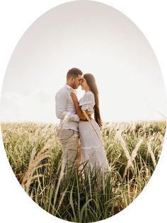 a man and woman standing in the middle of a field with tall grass on each side