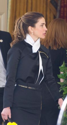 a woman in a black suit and white collared shirt standing next to another woman