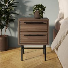 a bedroom with a bed, nightstand and plant on the side table in front of it