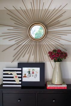 a sunburst is hanging on the wall next to a vase with flowers in it