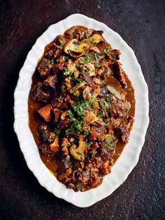 a white plate topped with meat and veggies covered in gravy on top of a table