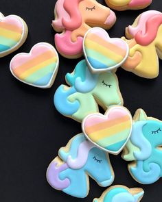 cookies decorated with pastel colors and unicorns are on a black surface, including one cookie