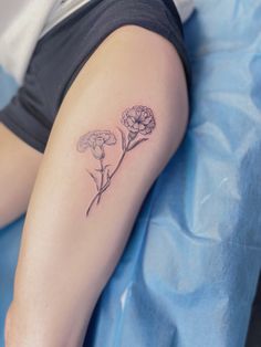 a person laying on a bed with a flower tattoo on their arm