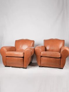 two brown leather chairs sitting next to each other