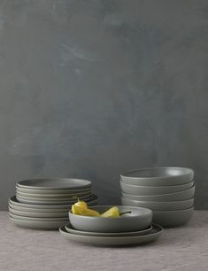 a stack of grey plates and bowls on a table