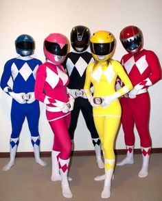 five people in colorful costumes standing next to each other wearing helmets and bodysuits