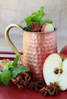 a copper mug filled with apples and cinnamons