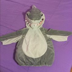 a stuffed animal sitting on top of a purple bed covered in a shark blanket and covering it's head