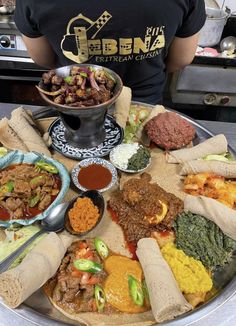 a person standing in front of a platter with different food items and sauces on it