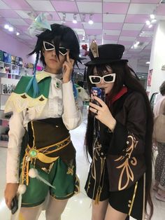 two people dressed in costumes standing next to each other while looking at their cell phones