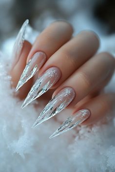 This Artistic Wonderland Nails design features sharp, elongated icicle-inspired nails with a translucent base and delicate white veins. Subtle glitter accents enhance the frosty look, making these Christmas nails the perfect blend of winter elegance and frosty glamour. A luxurious and cold beauty, ideal for the holiday season.   #ArtisticWonderlandNails #ChristmasNails #IcyNailDesign #FrostyNails #WinterNails #HolidayNailArt #IcicleNails #CrystalNailArt #LuxuryNails Stilleto Christmas Nail Designs, Christmas Nails Sharp, Stiletto Nail Art Christmas, December Nails Stilleto, Snow Nails Almond, Winter Pointy Nails, Frosty Nails Acrylic