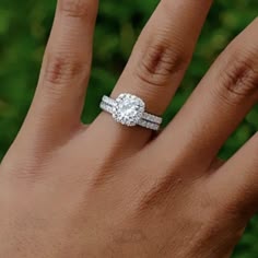 a woman's hand with a diamond ring on top of her finger and the other hand holding an engagement ring