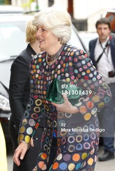 the woman is walking down the street with her hand on her hip and wearing a colorful dress