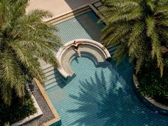 an aerial view of a pool surrounded by palm trees