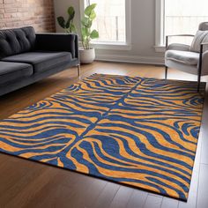 a blue and yellow rug in a living room with two couches, one is facing the window