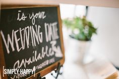 a chalk board with writing on it sitting next to a potted plant