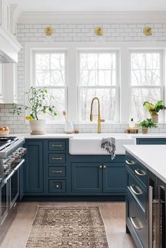 a kitchen with blue cabinets and white counter tops, gold faucets, brass pulls