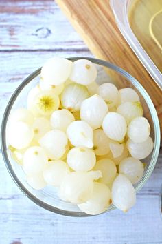 a glass bowl filled with white flowers next to a cutting board