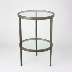 a round glass table with metal legs on a plain white background, it appears to be an end table or side table