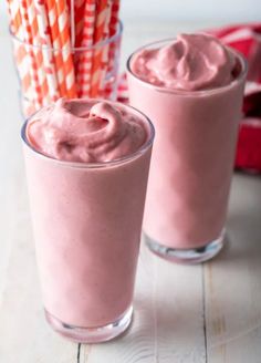 two glasses filled with pink smoothie and straws