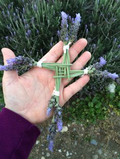 a person holding up some flowers in their hand with the cross made out of them