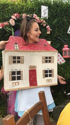 a woman holding up a doll house on top of her head