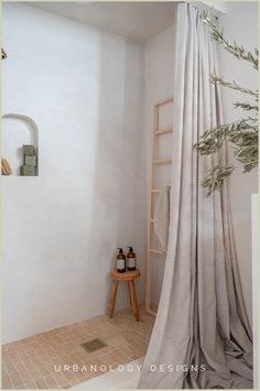 a bathroom with a shower curtain and two bottles on the floor next to a stool