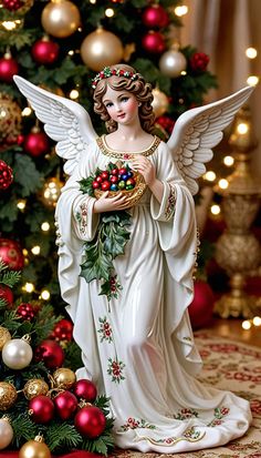 a statue of an angel holding a wreath in front of a christmas tree with red and gold ornaments