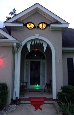 the front entrance to a house with two yellow eyes on it's face and mouth