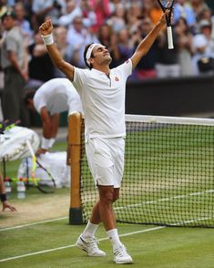 a male tennis player is celebrating his victory on the court with his arms in the air