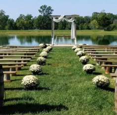 rows of wooden benches lined up with flowers in front of a lake and gazebo