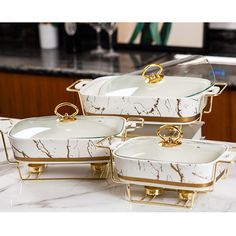 four white and gold dishes on a marble counter