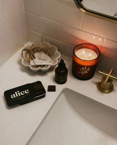 a bathroom sink with a candle, soap and other items on it